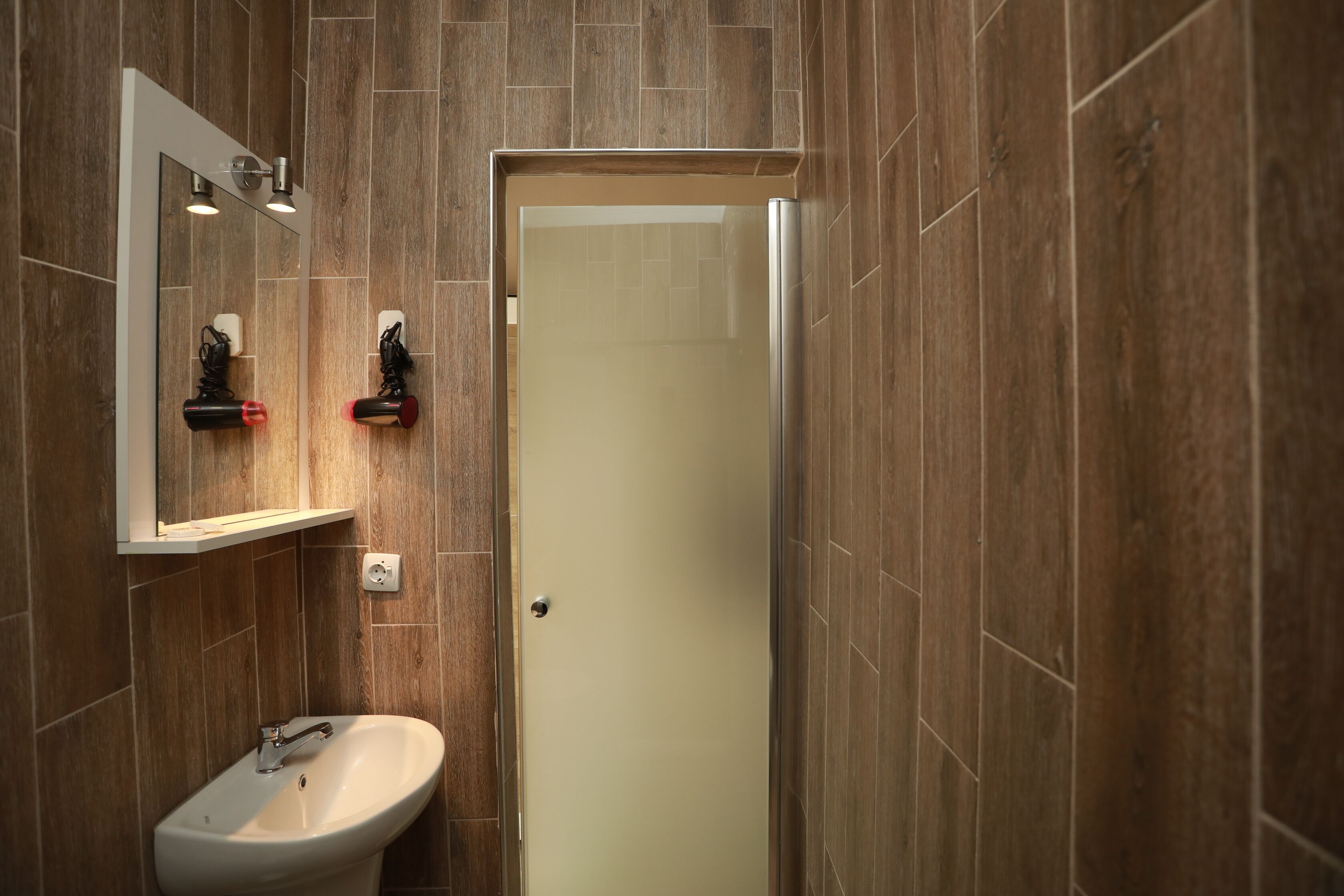 Un baño moderno con pared de madera, un lavabo y un espejo.