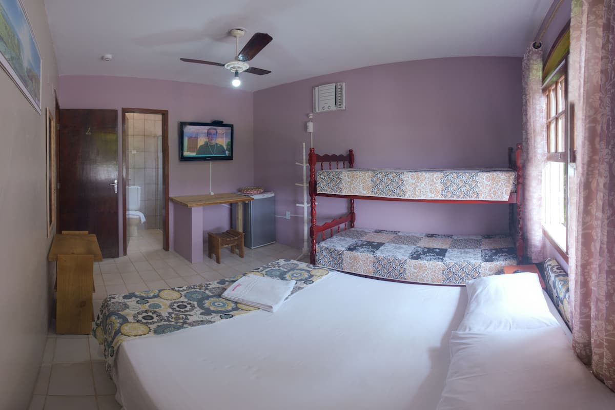 Une chambre avec des lits superposés, un bureau, une chaise et un téléviseur.