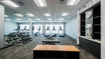 Un gimnasio con cintas de correr, mancuernas y máquinas de pesas.