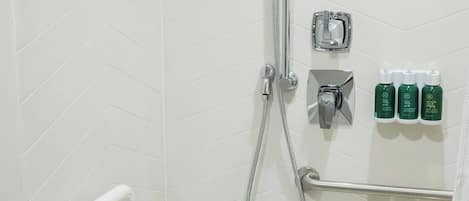 Zona de ducha con cabezal de ducha manual, panel de control en la pared y un perchero.