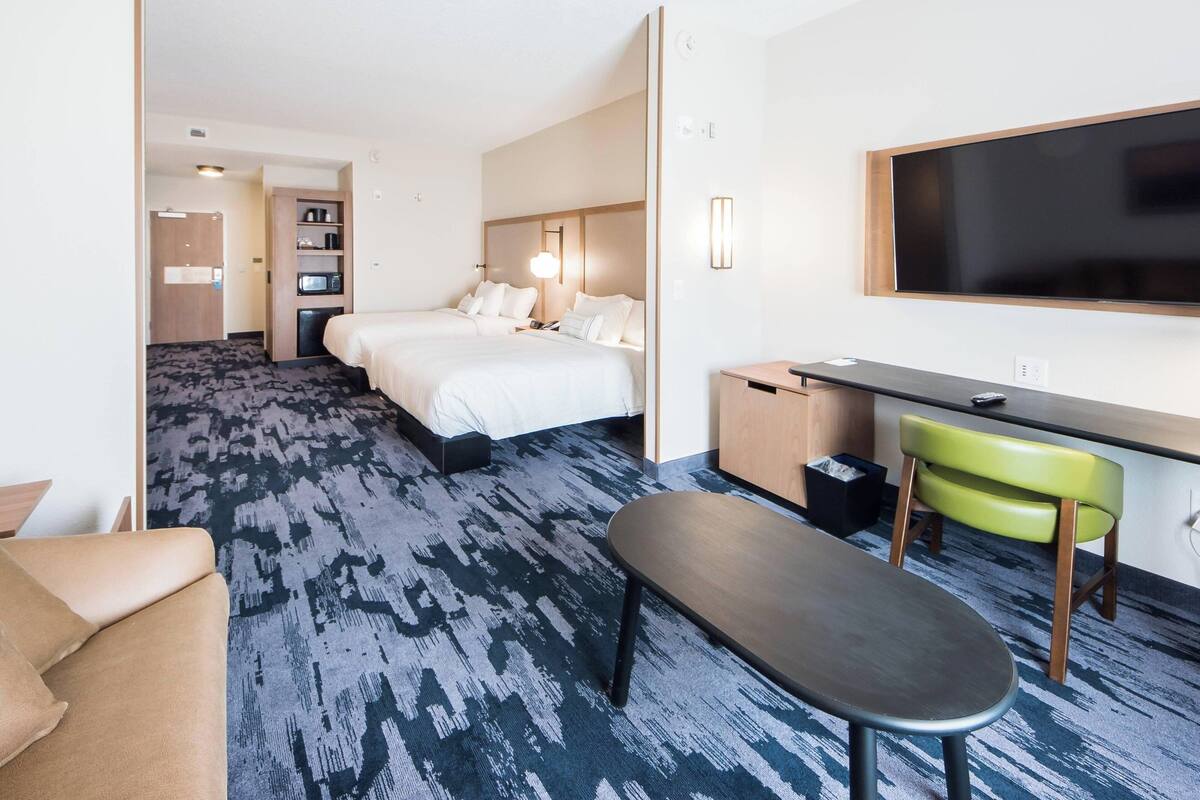 A hotel room with a large bed, a desk, a chair, and a television.