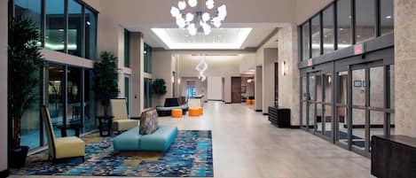 A spacious lobby with a modern chandelier, seating areas, and a reception desk.