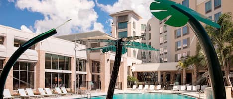 Una piscina con sillas de descanso y un edificio moderno al fondo.