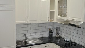 A modern kitchen with white cabinets, a stainless steel sink, and a black countertop.
