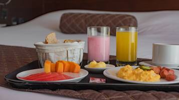 Una bandeja de desayuno con diversos alimentos y bebidas sobre una cama.