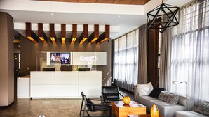 A modern hotel lobby with a reception desk, seating area, and large windows. - Hotel Rennova (La Paz)