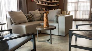 A modern living room with a sectional sofa, a round coffee table, and a bookshelf filled with books and decorative items.