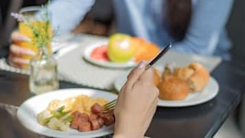 Una mesa de comedor con platos de comida, un vaso de zumo de naranja y una botella de agua.