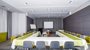 Une salle de conférence équipée d’une longue table, de nombreuses chaises, d’un écran de projection et d’un pupitre.