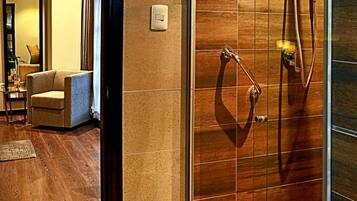 Un baño moderno con cabina de ducha de vidrio, suelo de madera y un perchero visible.