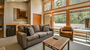 A spacious living area with a sofa, coffee table, and a view of a deck and forest. - Keystone Bristlecone Home 31 (Keystone)