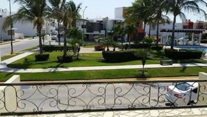 A modern building with a parking lot, palm trees, and a white car parked on the street.