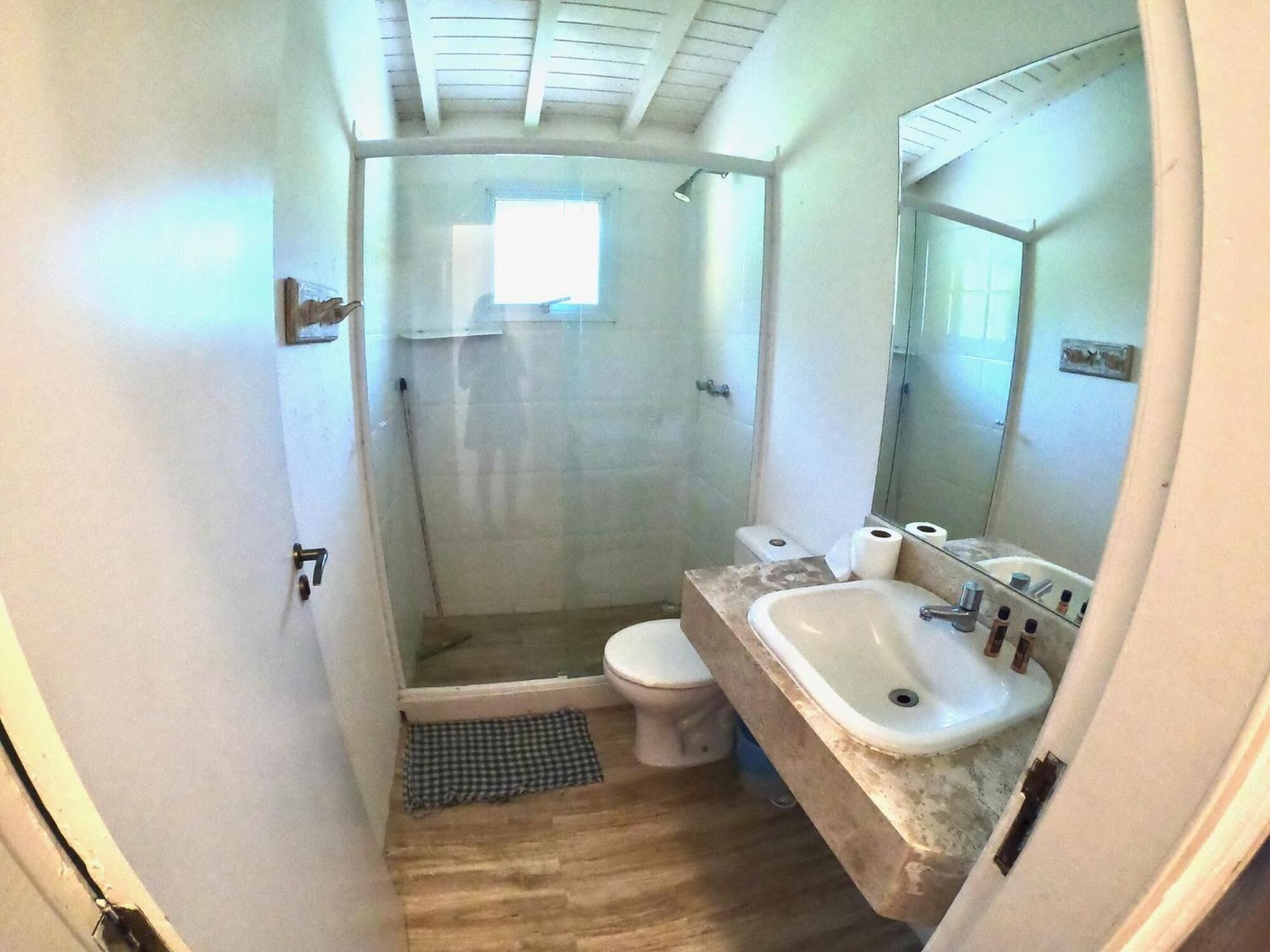 Une petite salle de bain compacte, équipée d’une douche, de toilettes et d’un lavabo.