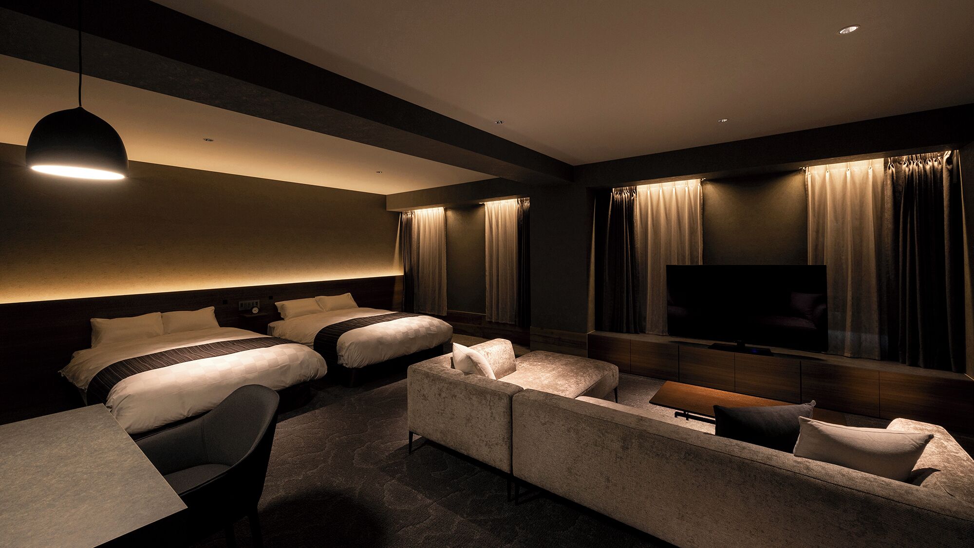 Une chambre d’hôtel avec deux lits, un canapé, une télévision et un bureau.