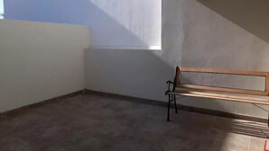A corner room with a bench, a window, and a tiled floor.