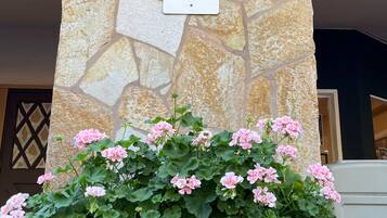 Muro de piedra con señal de estacionamiento para registro y una jardinera grande con flores rosadas.