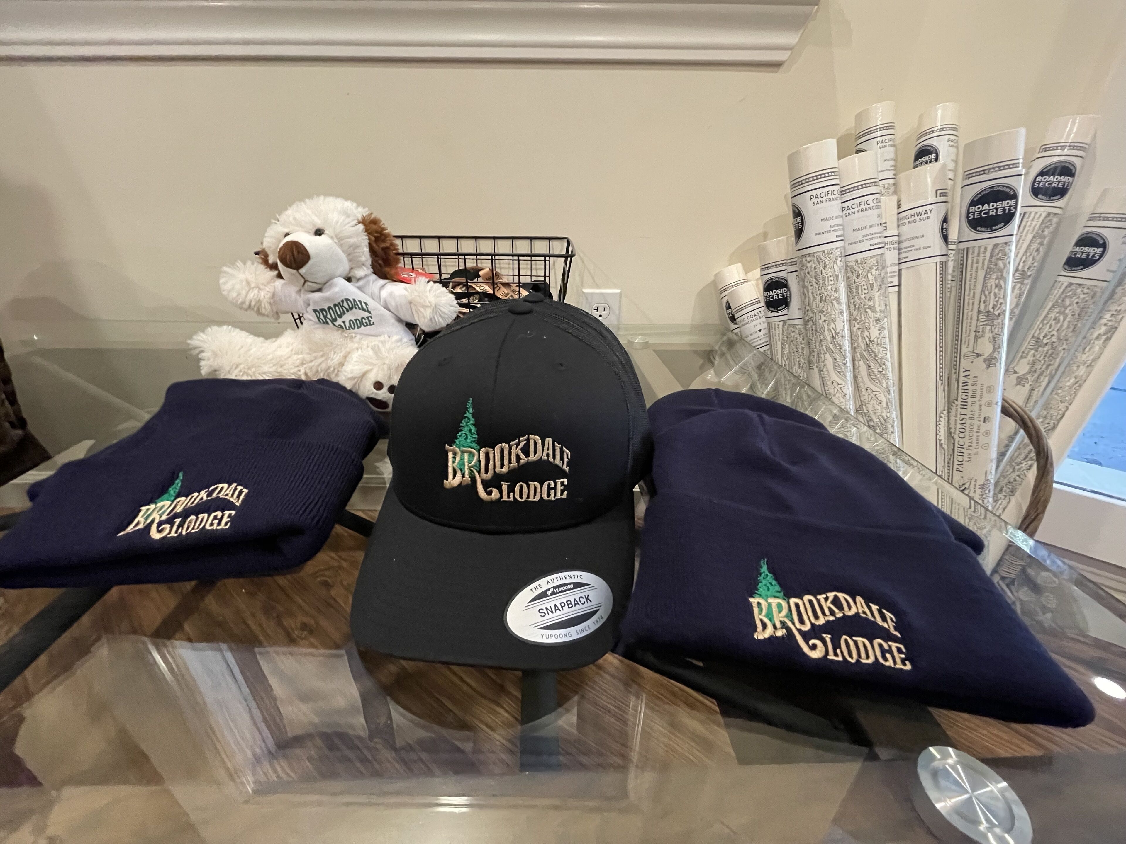 A display of Brookdale Lodge branded items including a cap, sweatshirts, and a stuffed animal.