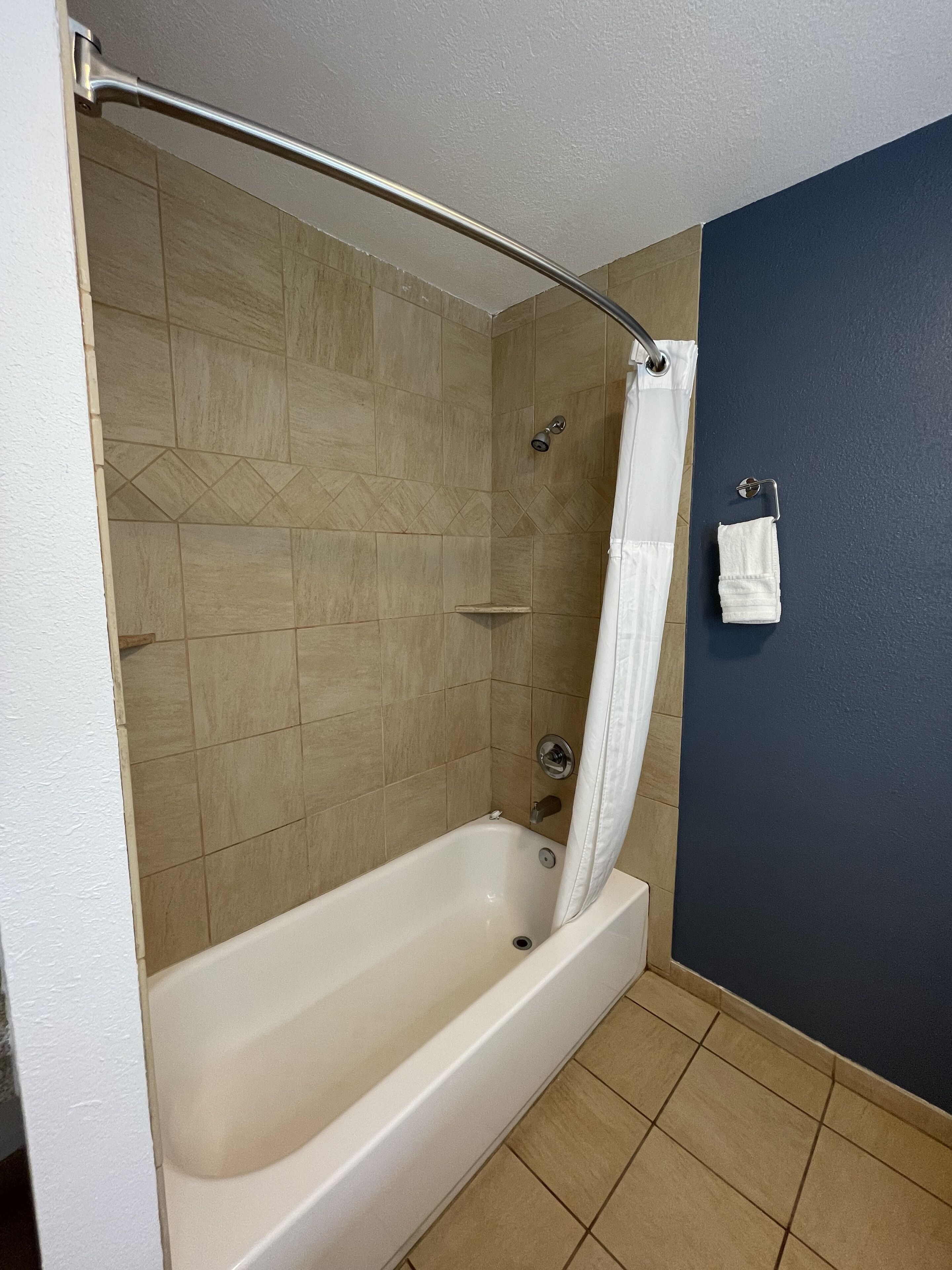 A bathroom with a bathtub, shower curtain, and a towel rack.