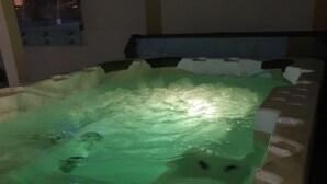 A hot tub with a green cover, a black seat, and a white base. - Heritage Apartment (Auckland)