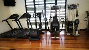 A gym with treadmills, elliptical machines, a bench press, and weight machines. - Heritage Apartment (Auckland)