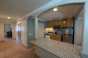 A kitchen with granite countertops, wooden cabinets, stainless steel appliances, and a recessed ceiling light.