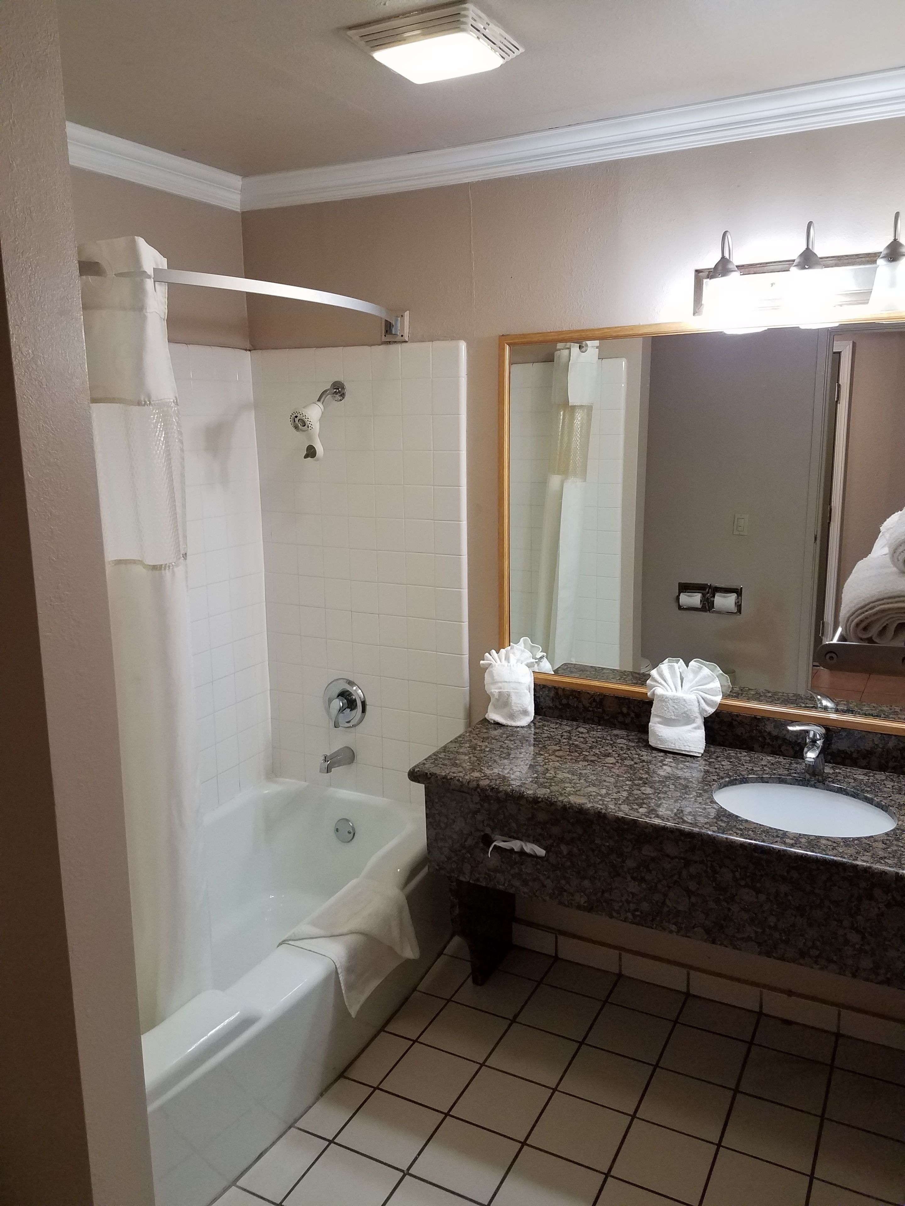 A bathroom with a bathtub, a sink, and a mirror.