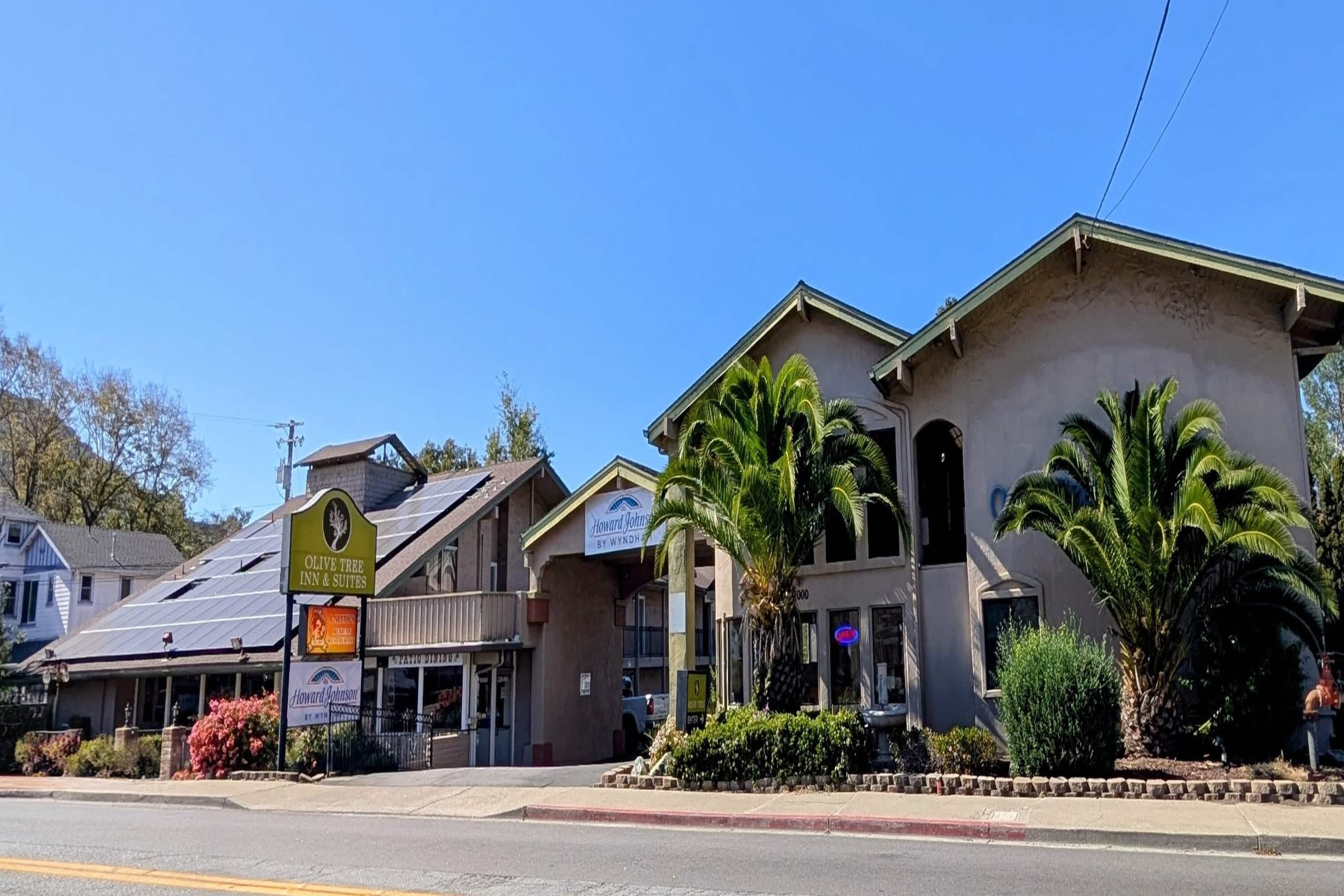 A hotel with a sign for 'Howard Johnson's by Wyndham,' a parking lot, and a street view.