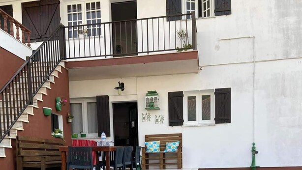 A courtyard with a table set for two, two glasses of red wine, and a bench. - Casa Praia da Nazare (Nazaré)