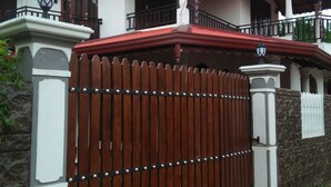 Uma casa com portão de madeira, telhado vermelho e varanda.