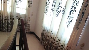 Uma escadaria com cortinas estampadas e um corrimão de madeira.