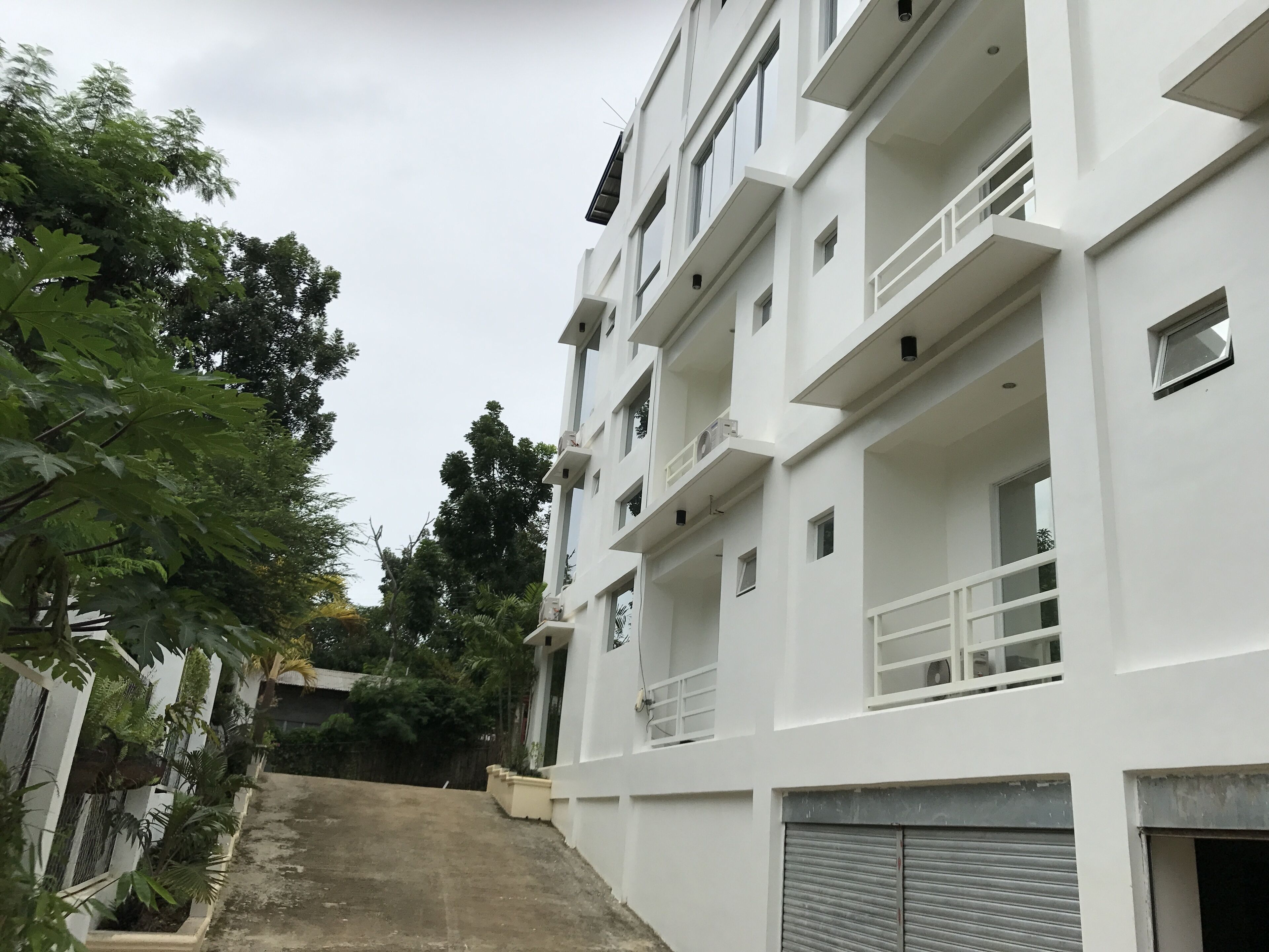 A multi-story white building with balconies, a staircase, and a garage door.