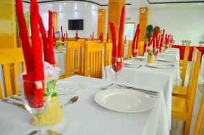 A restaurant with white tablecloths, red napkins, and neatly set dining tables.