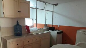 A compact kitchen with a gas stove, a water dispenser, and a small table.