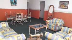 A room with patterned sofas, a sewing machine, a table, and a chair.