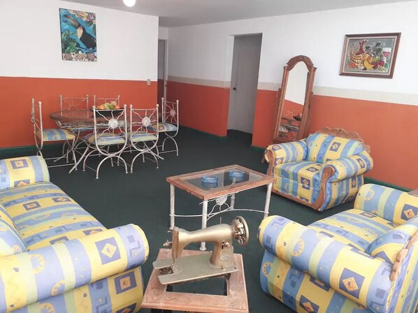A room with patterned sofas, a sewing machine, a table, and a chair.