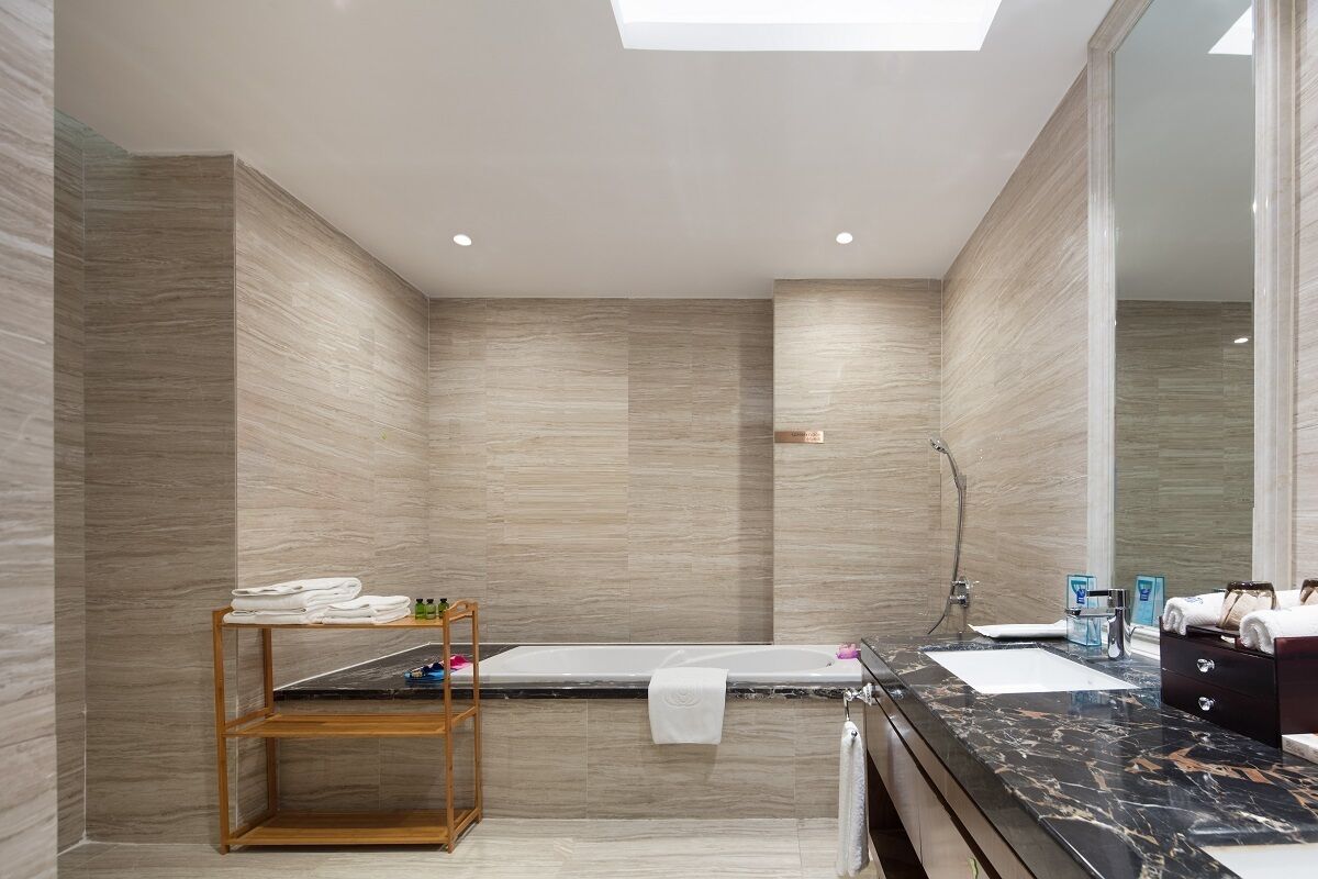 Un baño moderno con una bañera, un estante de madera con toallas y un espejo grande.