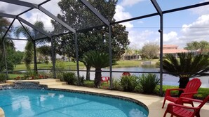 An indoor swimming pool with a view of a lake and surrounding greenery. - Tropical Waterview Mansion (Sarasota)