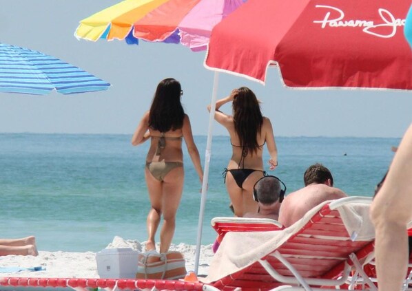 A beach scene with people in swimwear, beach umbrellas, and a lifeguard chair.