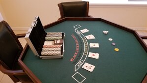 A blackjack table with cards and chips, surrounded by chairs. - Tropical Waterview Mansion (Sarasota)