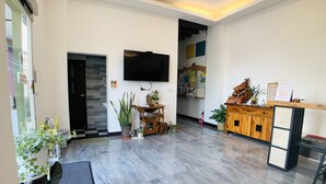 Un moderno vestíbulo de hotel con una televisión de pantalla plana, un mostrador de recepción y diversas plantas.