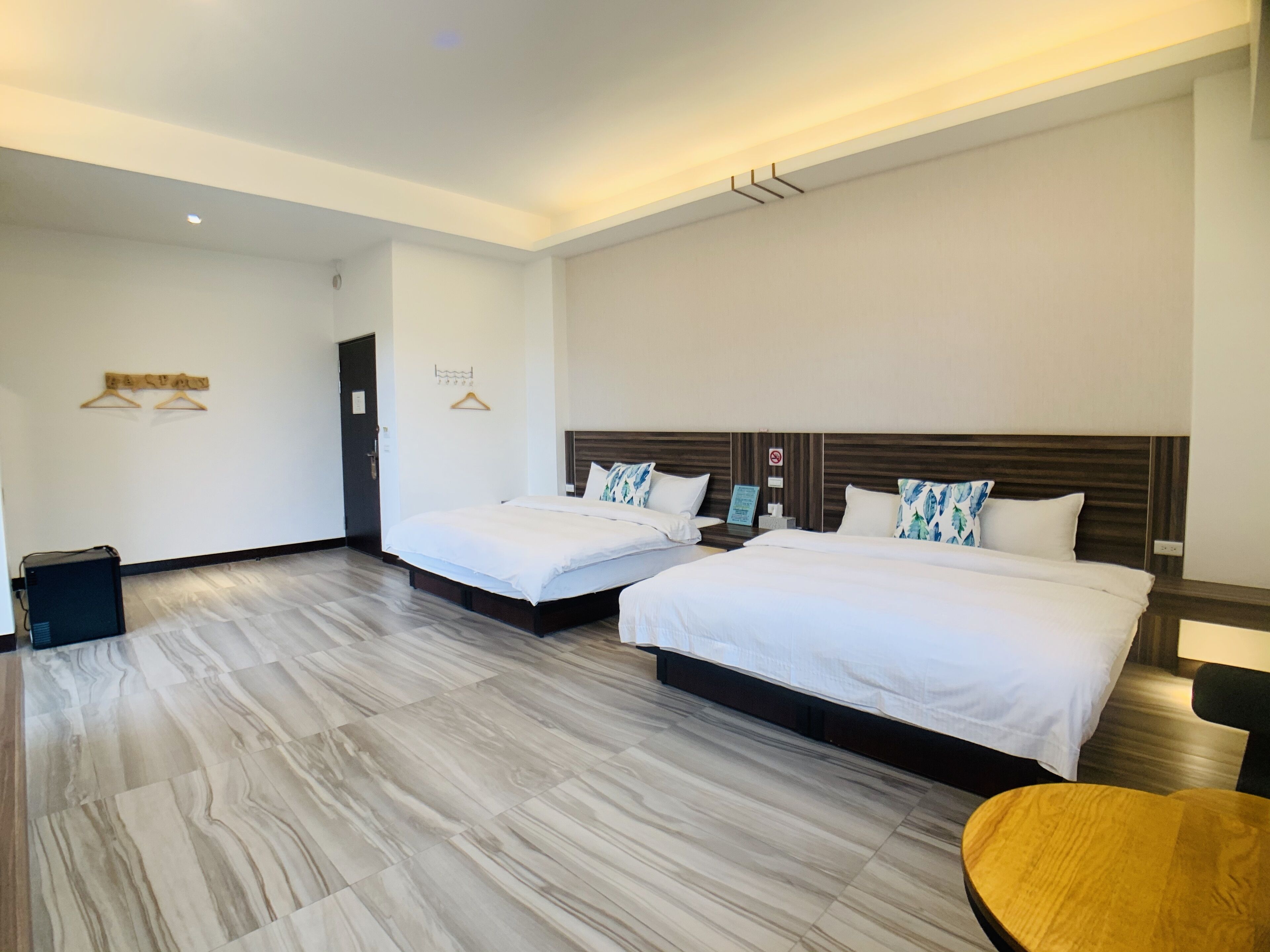 A hotel room with two beds, a wooden floor, and a small round table.
