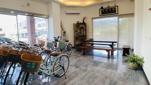 Una habitación con bicicletas, un banco de madera, una planta en maceta y una estantería.