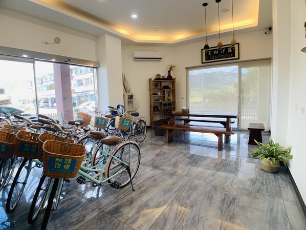 A room with bicycles, a wooden bench, a potted plant, and a bookshelf. - Xuyu B&B (Chishang)
