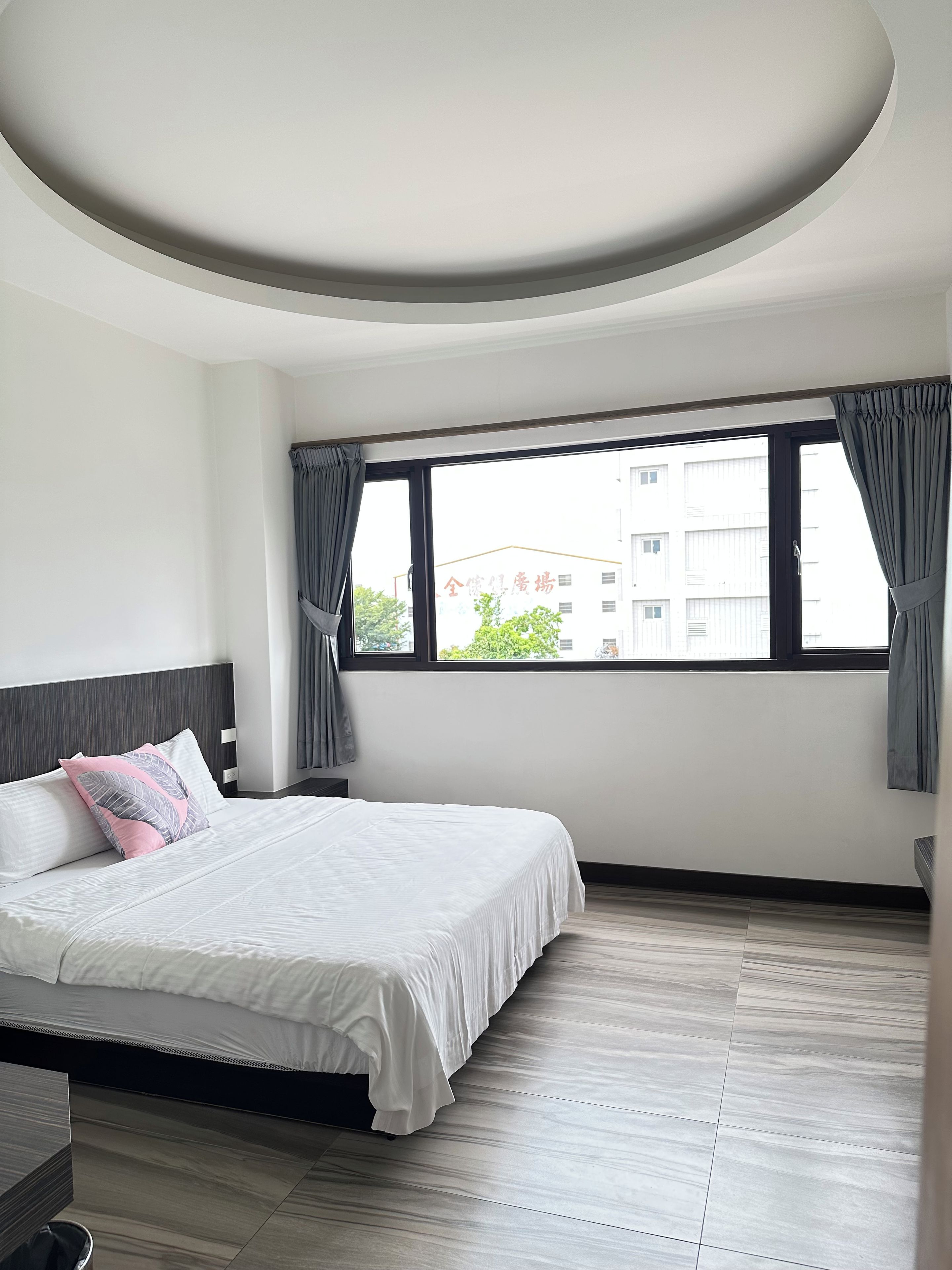 Une chambre moderne avec un grand lit, un plafond cintré et une fenêtre avec des rideaux.