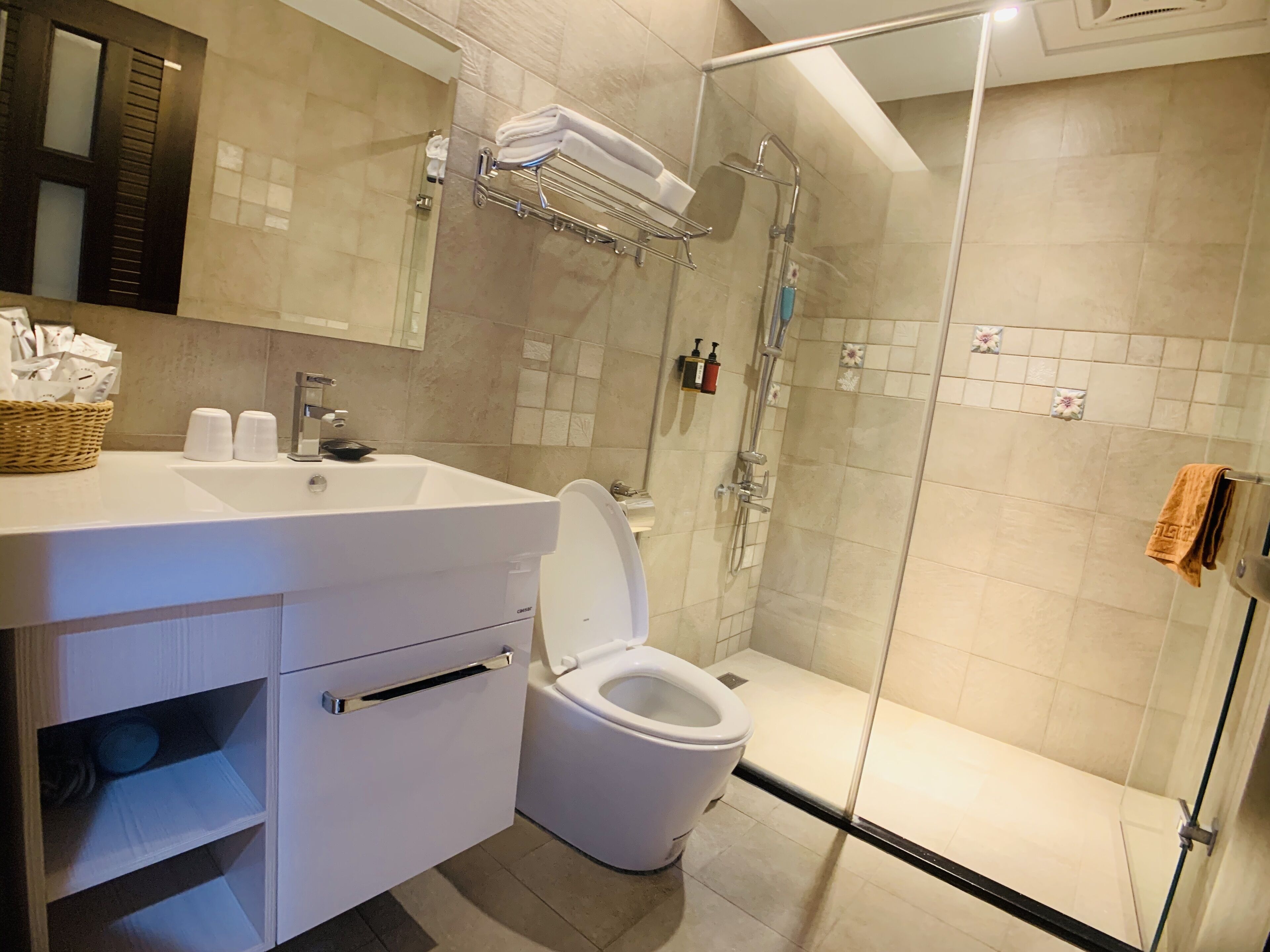 Een moderne badkamer met een douchecabine van glas, een witte wastafel en een toilet.