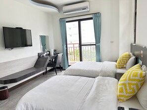 Une chambre d’hôtel avec un lit, un bureau, une chaise, une télévision et une fenêtre avec des rideaux.