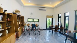 Una habitación amplia con suelo de mármol pulido, estanterías de madera, un comedor con sillas y bicicletas.