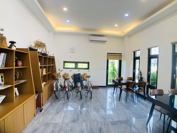 Una habitación amplia con suelo de mármol pulido, estanterías de madera, un comedor con sillas y bicicletas.