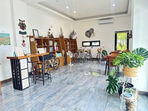 Une bibliothèque avec des étagères, un comptoir d’accueil, des vélos et des plantes en pot.
