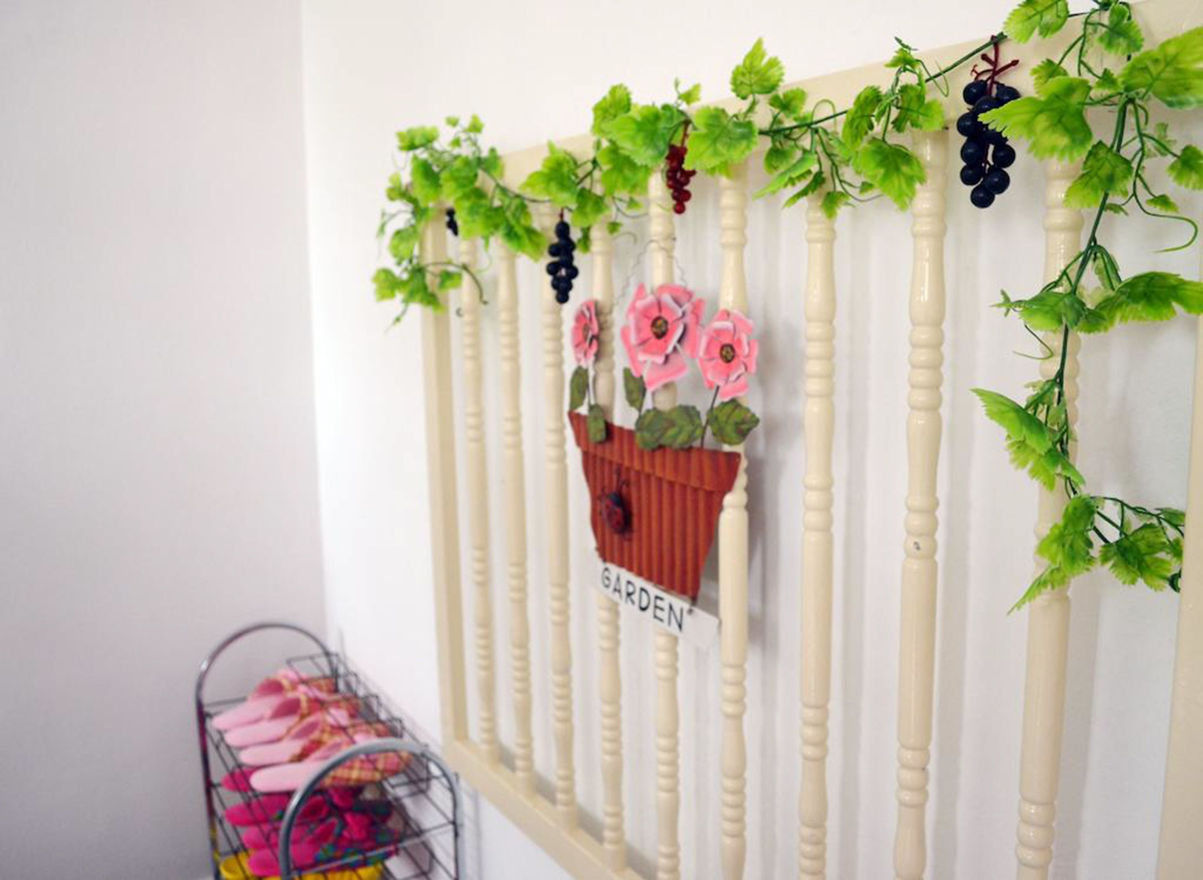 A wall with a white railing and a hanging planter with pink flowers and the word "GARDEN".